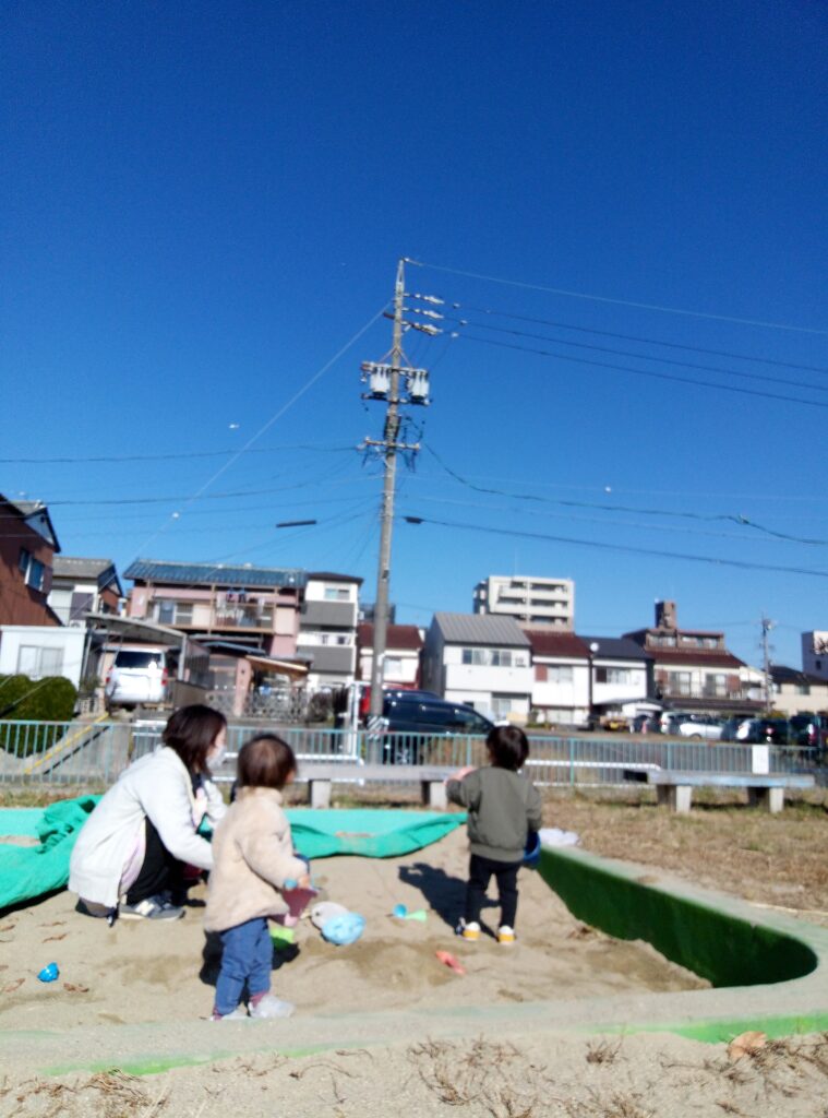 公園で遊ぶ園児と綺麗な青空